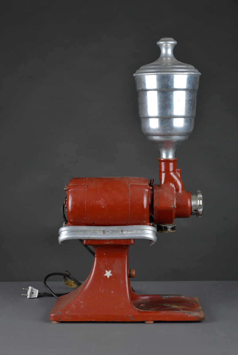 Motorisert kaffekvern som har stått i en landhandler. 
Kaffebønner helles i maskinen og males til kaffe, fortrinnsvis for kok-kaffe.

Det følger med en løs beholder for å samle opp den malte kaffen.

Maskina er rødlakkert, er slitt med noe rust og rester av olje eller fett.