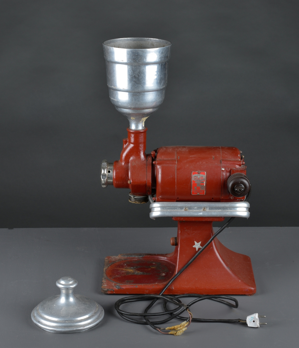 Motorisert kaffekvern som har stått i en landhandler. 
Kaffebønner helles i maskinen og males til kaffe, fortrinnsvis for kok-kaffe.

Det følger med en løs beholder for å samle opp den malte kaffen.

Maskina er rødlakkert, er slitt med noe rust og rester av olje eller fett.