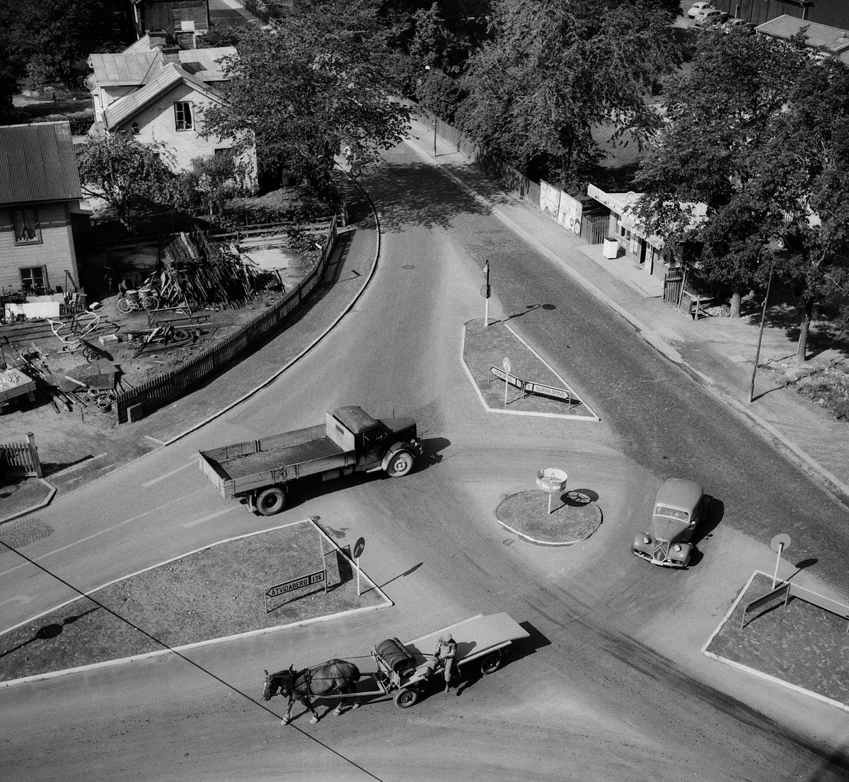 Lätta och tyngre trafikanter samsas i korsningen av Gamla och Nya Tanneforsvägarnas möte med infart till centrala Linköping. Perspektiv från höghuset Kannan som var under uppförande vid tiden. 1956.