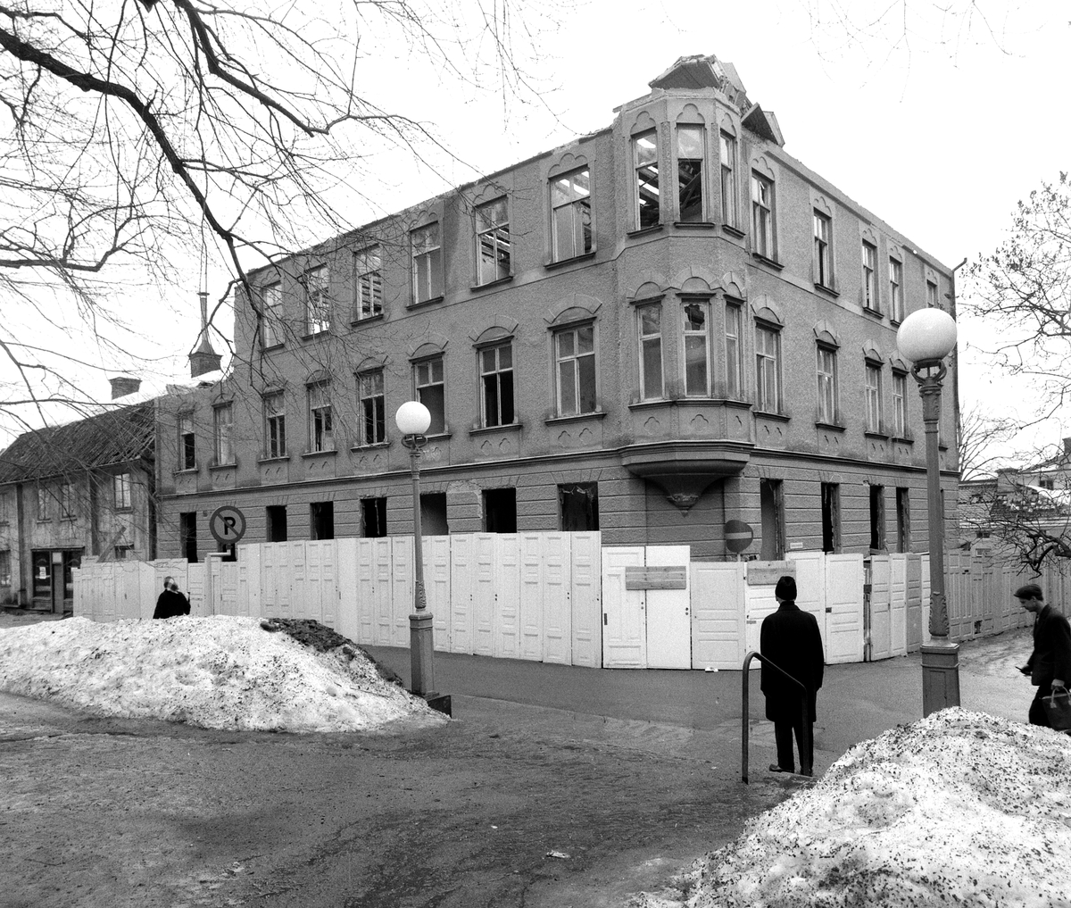 Apotekaregatan 15 i Linköping under rivning vintern 1965-66. Notera husets vackra innerdörrar som bildar byggplank. Vid rivningen var huset knappa 70 år (klart 1898) och gavs således likt många från tiden en relativt kort tid i funktion. Den en gång i tiden förhoppningsfulle byggherren var folkskolläraren Lars Alfred Gustafsson och som byggmästare finner vi möjligtvis stadsbyggmästare Anders Lundqvist (1834-1920).