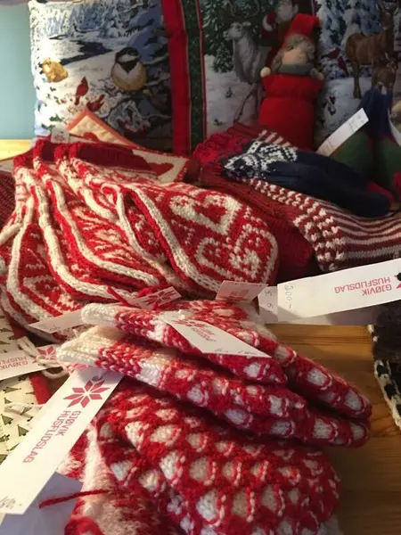 Ulike par røde og hvite strikkevotter med prislapp fra Gjøvik husflidslag på. Ligger på et bord, klar for julemarked.