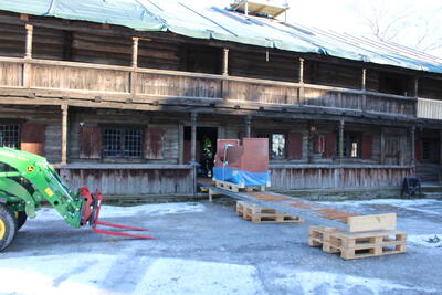 Bildet viser en traktor som skal løfte en pall med gjenstander fra bygget.