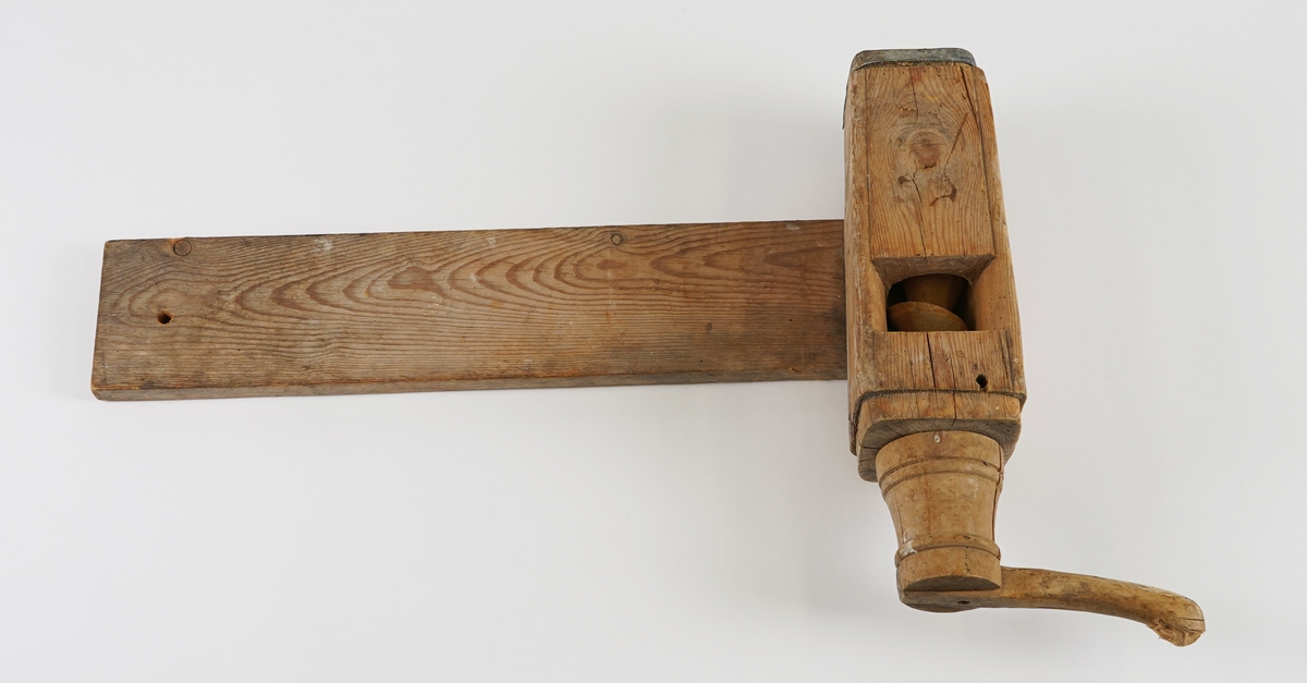 Potetkvern i tre. Består av eit trebrett/plank som underlag, ein sylinder med ei skrue inni, og ei sveiv.