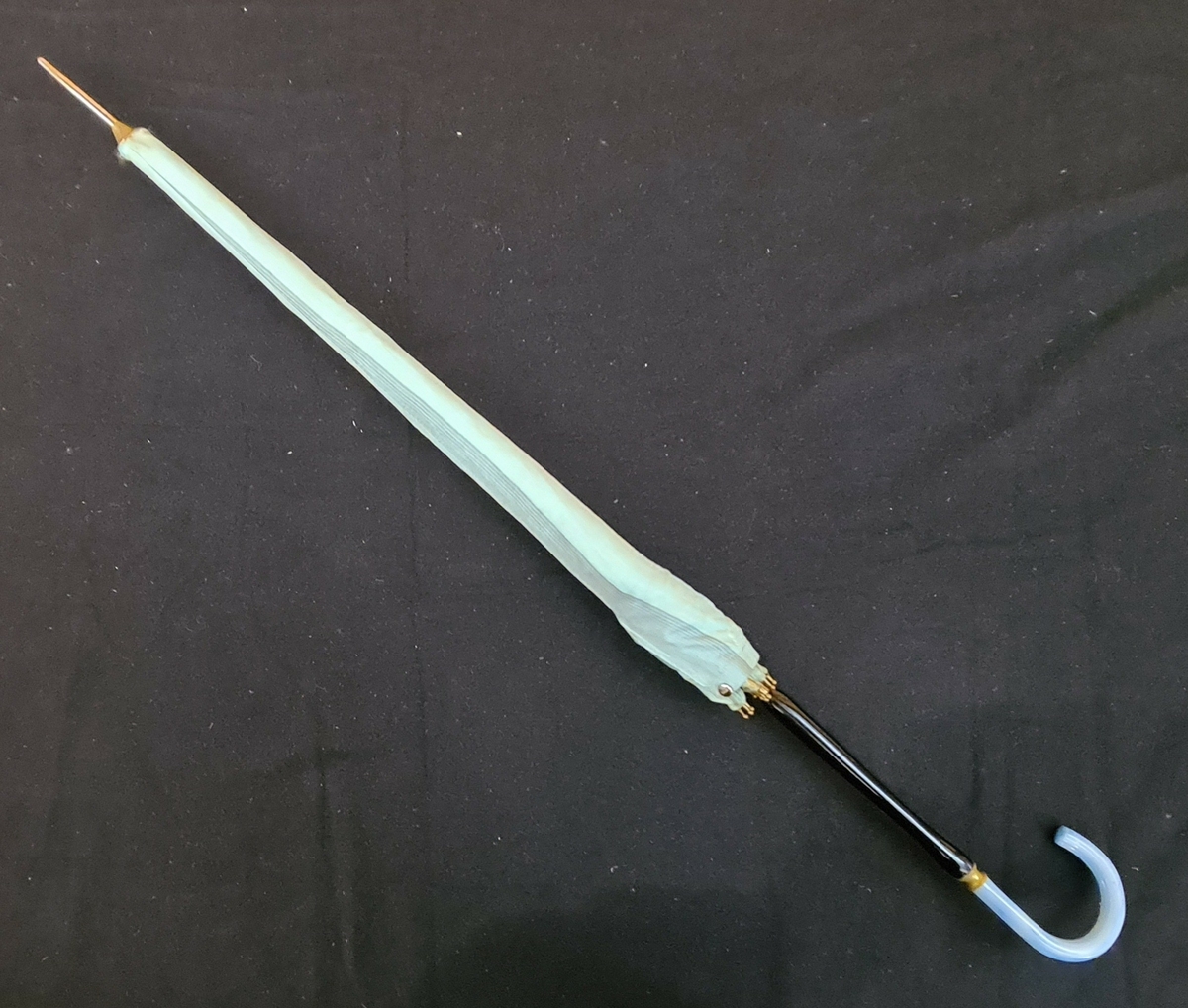 Blågrönt paraply med fodral och svart skaft och blå krycka.

Köpt 1960 eller 61 i Lugano Italien av Eva Granat.