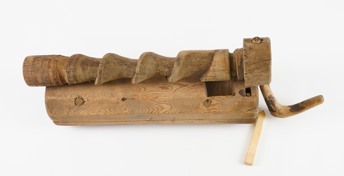 Potetkvern i tre. Består av ein sylinder med ei skrue inni, og ei sveiv. Ny låsepinne.