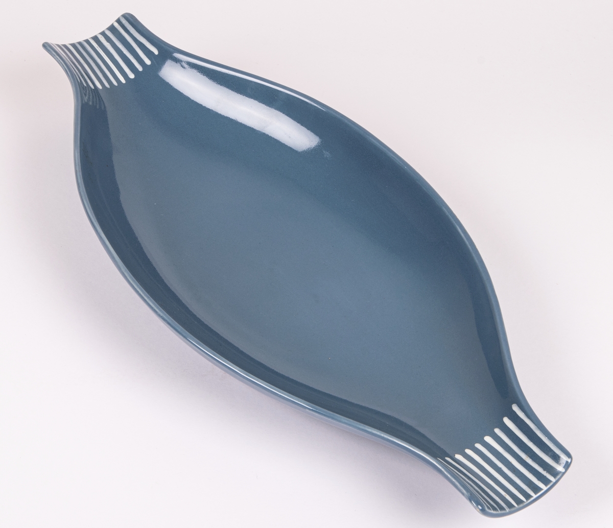 Skål i flintgods, modell M20 av Lillemor Mannerheim, formgiven 1957. Grå glasyr med vita ränder vid kortsidorna.