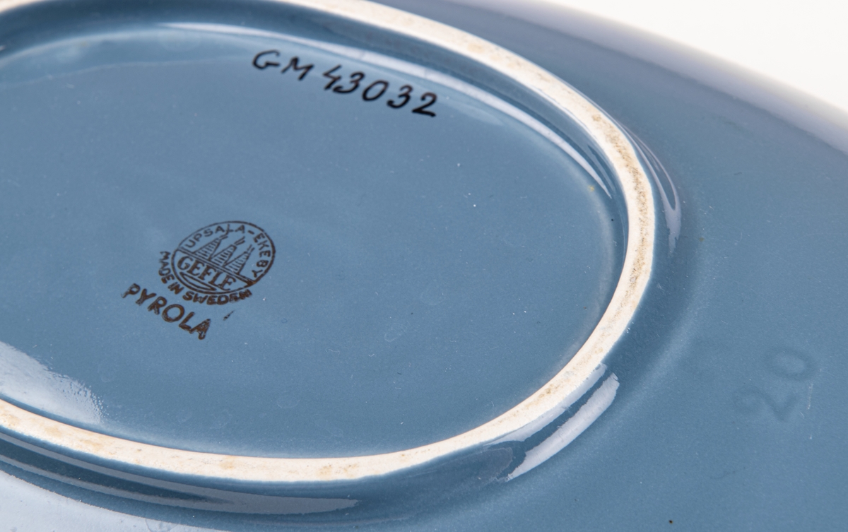 Skål i flintgods, modell M20 av Lillemor Mannerheim, formgiven 1957. Grå glasyr med vita ränder vid kortsidorna.