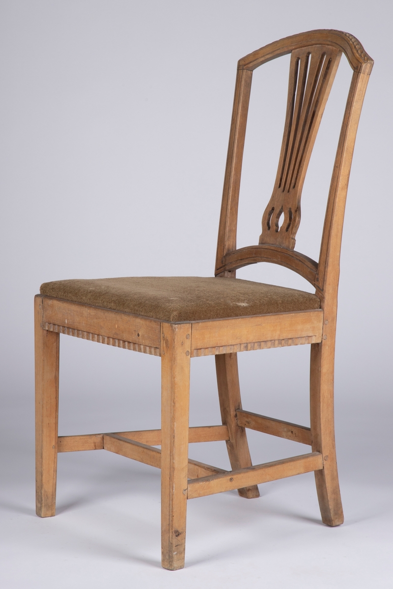 Rette, firkantete forben med enkel strek som dekor på hjørnene foran. Rettlinjet sarg, noe svsmalnende bakover og med enkel hulkilsbord langs underkanten av for- og sidesarger. H-kryss med rette sprosser, og en bindingsspross mellom bekbenene. Disse er firkantete med svak buing innover og bakover, og fortsetter opp i de avsmalnende, bakut og utadsvugne akterstavene. Buet toppstykke med enkel, skåret bladbord på overkanten. Gjennombrutt, vifteformet ryggbrett, oppdelt i fem spiler og gjennombrutt mønster nederst over festet i den buete tverrsprossen. Hele ryggrammen på fremsiden dekorert med to parraleltgående skråne striper. Fikk nytt beige velourtrekk fra Sellgrens veveri i 1939.