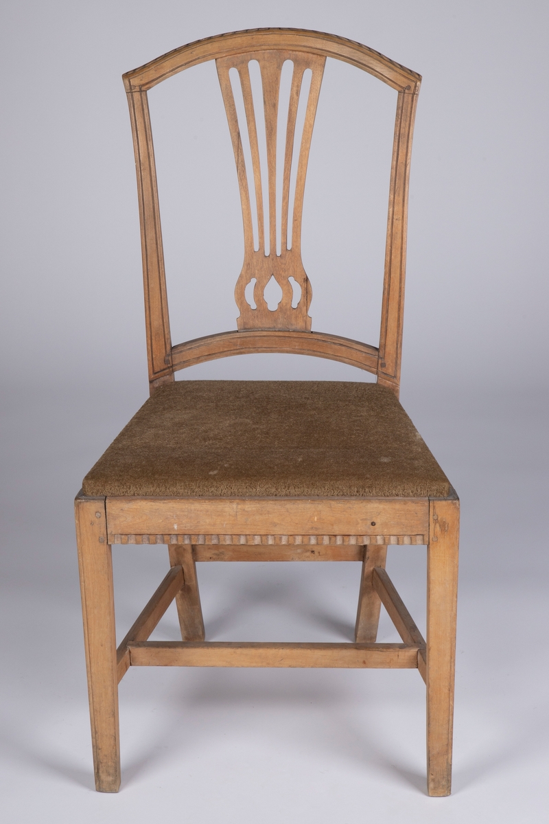 Rette, firkantete forben med enkel strek som dekor på hjørnene foran. Rettlinjet sarg, noe svsmalnende bakover og med enkel hulkilsbord langs underkanten av for- og sidesarger. H-kryss med rette sprosser, og en bindingsspross mellom bekbenene. Disse er firkantete med svak buing innover og bakover, og fortsetter opp i de avsmalnende, bakut og utadsvugne akterstavene. Buet toppstykke med enkel, skåret bladbord på overkanten. Gjennombrutt, vifteformet ryggbrett, oppdelt i fem spiler og gjennombrutt mønster nederst over festet i den buete tverrsprossen. Hele ryggrammen på fremsiden dekorert med to parraleltgående skråne striper. Fikk nytt beige velourtrekk fra Sellgrens veveri i 1939.