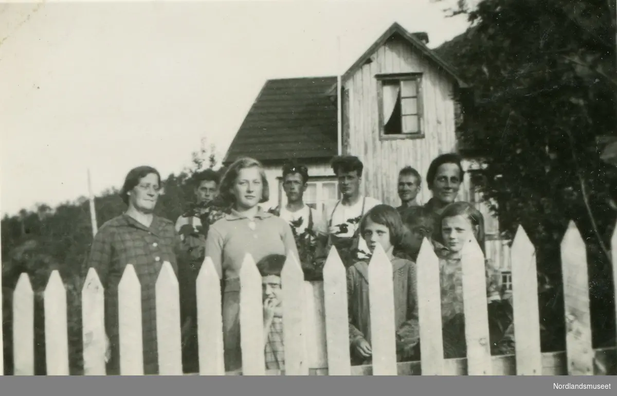 Voksne og barn samlet på gården  Liland i Steigen.
De voksne fra venstre: Pauline, Reidar, Olaug, Eilif, Bjarne, Ole Olsen og Janny Kristensen.
I bakgrunnen er huset til Pauline og Ole Olsen.