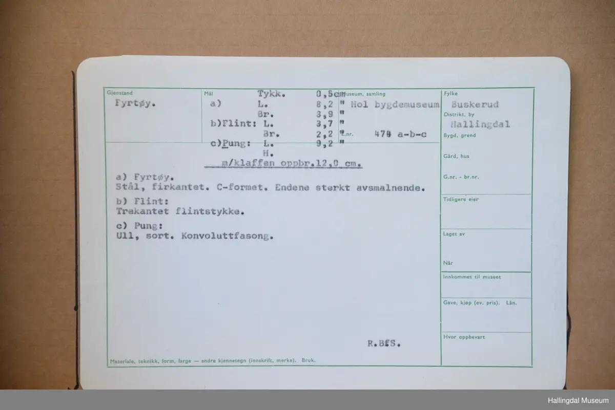 a) Ildstål, firkantet, C-formet, endene sterkt avsmalnende. L: 8,2 cm, br: 3,9 cm 
b) Flint-trekantet flintstykke
c) pung, ull, sort, konvoluttfasong. L: 9,2 cm, Br: 2,2 cm.