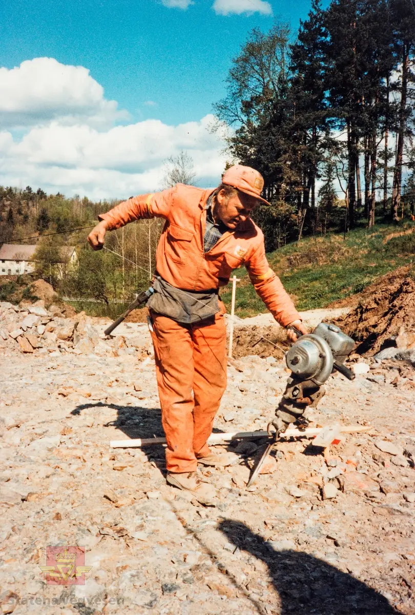 Startvansker - Håndholdt bormaskin.  
Leon R. Lorentzen, formann i snekkergjengen med håndholdt, bensindrevet bormaskin på E-18 anlegget Østerholtheia - Brokelandsheia som ble åpnet i 1989.
 Bildet er fra jubileumsutstillingen i 1989. Tema: "Her skal veien gå".  Boremaskinen er en Atlas Copco, mod. Cobra.  
Navn på personer: Formann Leon R. Lorentzen.

Stedsnavn: Sunde