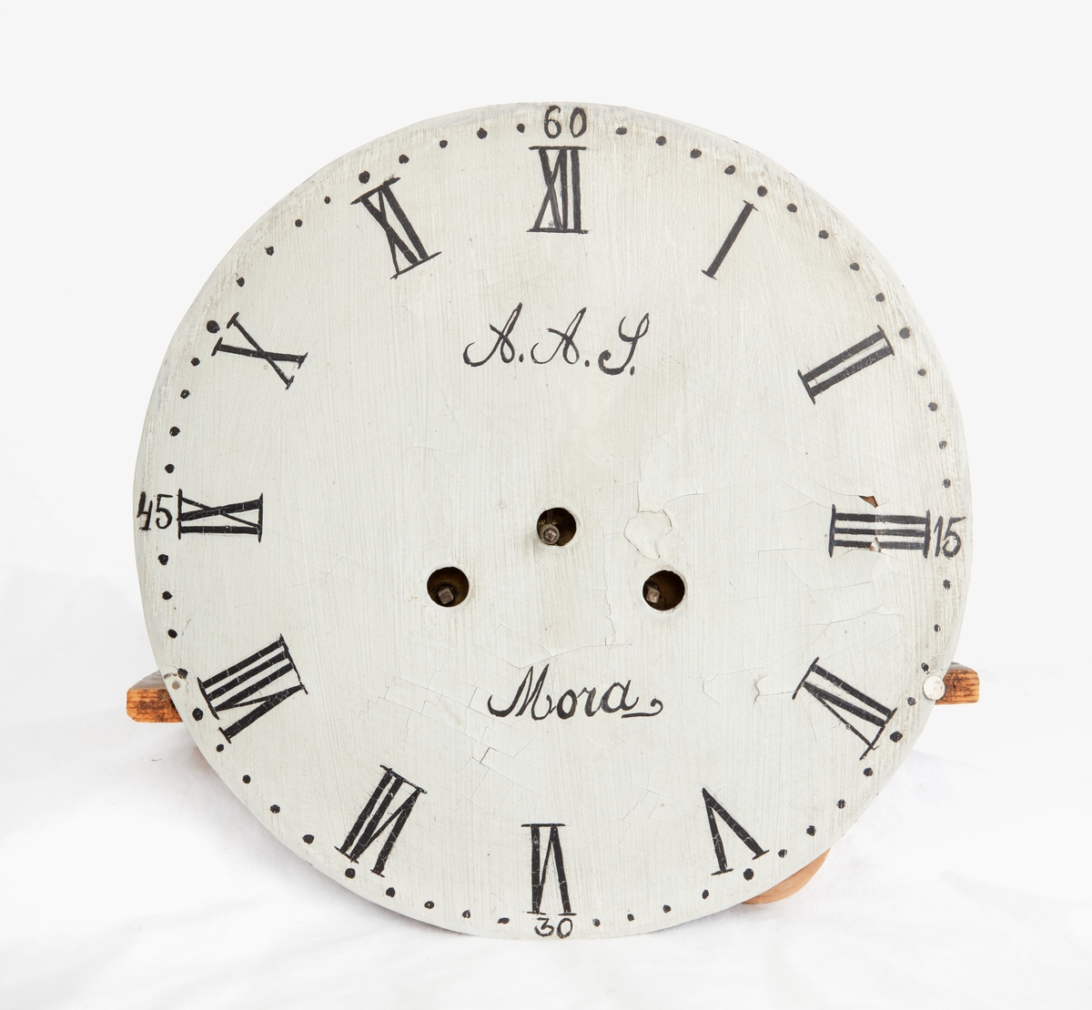 Ståndur. Mässing och trä. Fodral av svängd modell målat blågrönt, lister och kantbårder svart med ranka i rött och vitt samt röd konturlinje, huven daterad: "ANNO 1810". Verk med vitmålad urtavla, romerska siffror, signatur: "A.A.S. Mora", genombrutna visare av mässing, lod och pendel saknas. På baksidan signatur: I. M.M.. Defekt, lagad.