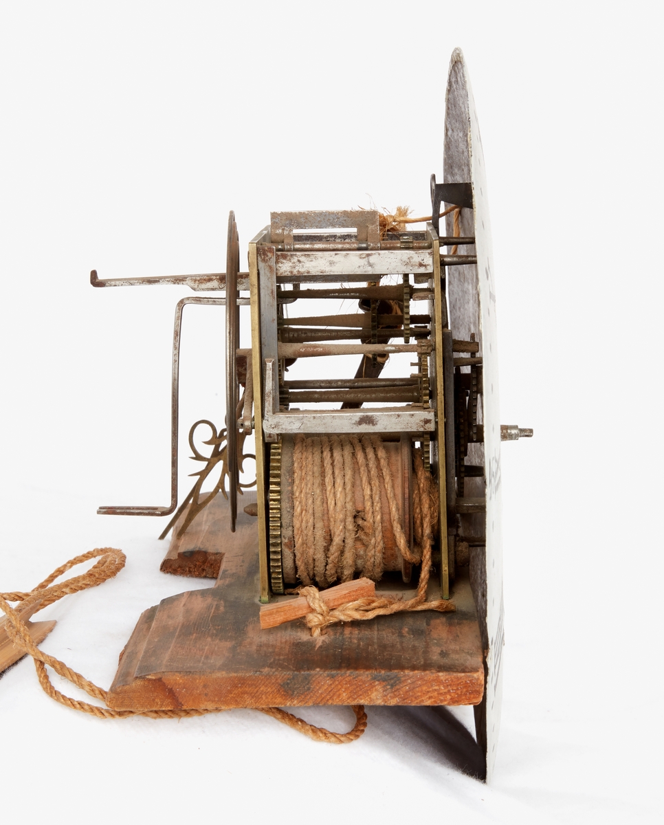 Ståndur. Mässing och trä. Fodral av svängd modell målat blågrönt, lister och kantbårder svart med ranka i rött och vitt samt röd konturlinje, huven daterad: "ANNO 1810". Verk med vitmålad urtavla, romerska siffror, signatur: "A.A.S. Mora", genombrutna visare av mässing, lod och pendel saknas. På baksidan signatur: I. M.M.. Defekt, lagad.