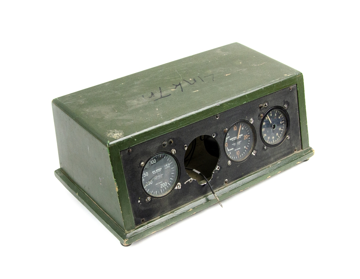 Linktrainer Instrumentpanel, till simulator. Rektangulär trälåda i grönt utförande, instrumentpanelen har fyra mätare varav en av dessa saknas. I utbildningssyfte.