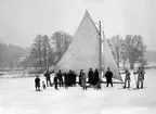 Nöje på sjön Roxens is vintern 1904. Vid sidan av mindre åkdon som kälke, spark och skidor, tornar järnhandlare Mauritz Hydéns imponerande isjakt. Här har sällskapet stannat upp för posering utanför Korsvik i Roxenbaden.