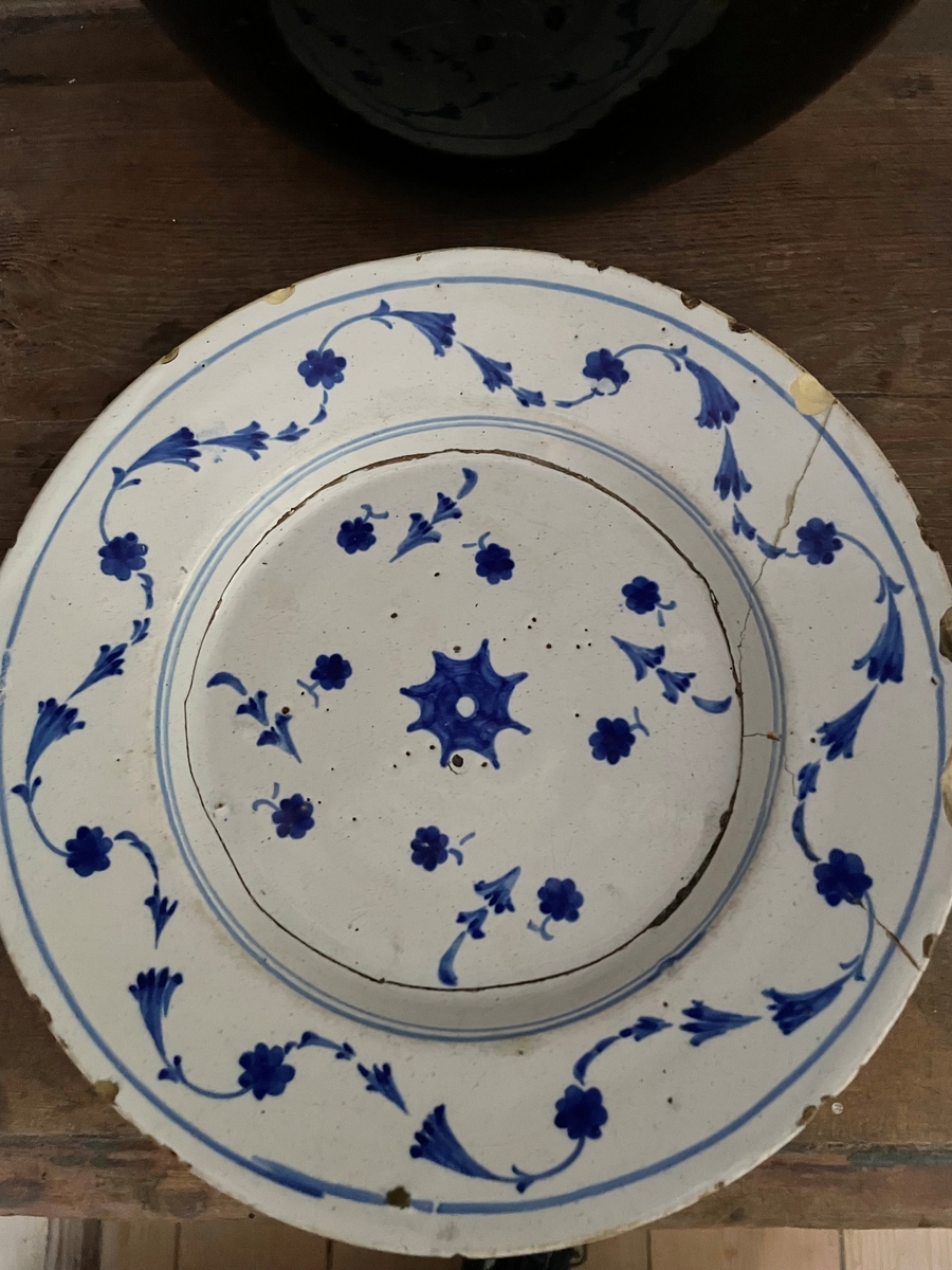 En tallrik av fajans som är vitglaserat med ströblommor i mörkblått.