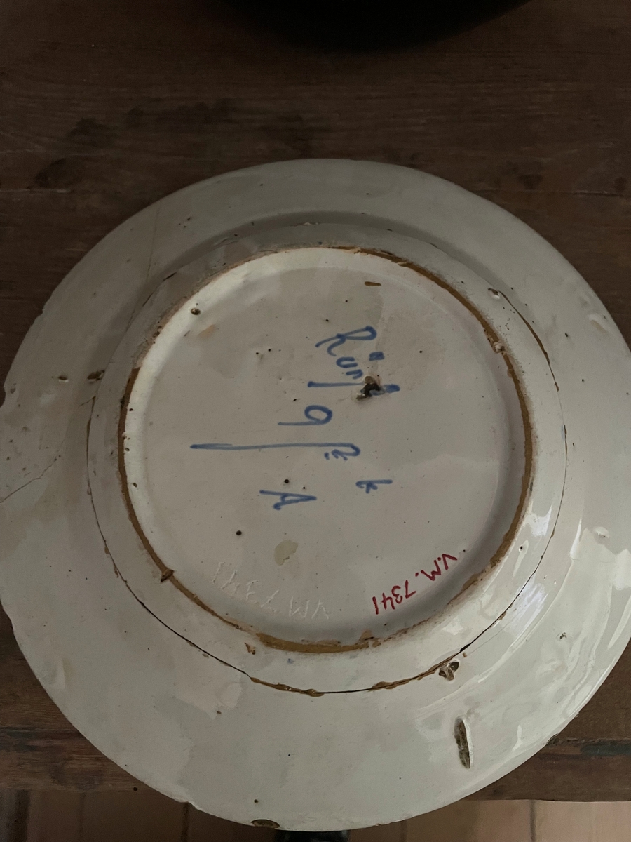 En tallrik av fajans som är vitglaserat med ströblommor i mörkblått.