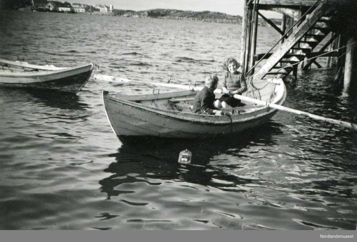 To barn i en robåt utenfor kaia på Nordskot. Søsknene Gabi og Wolfgang fra Tyskland på sommeropphold en gang etter krigen. Gjerne kalt sommerbarn.