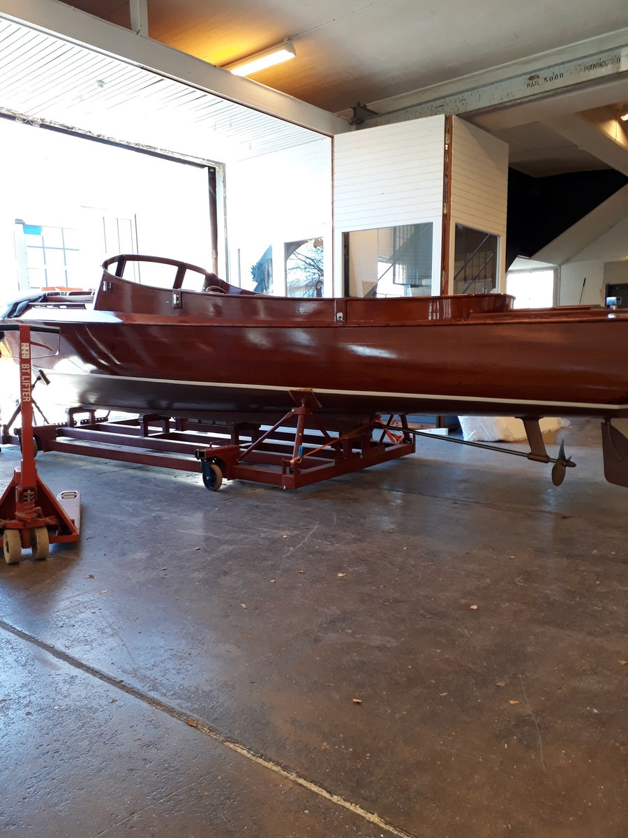 Kravellbyggd mahognymotorbåt, s.k. "Forslundsracer". Byggd på Sjöexpress varv på Lidingö 1928–1929.
Tillbehör till båten: 2 korgstolar, 7 dynor, 2 durkmattor, 1 kapell med bågar, 1 svensk flagga, 1 standert, 6 däcksmattor, 1 par åror i mahogny, 1  båtshake i  mahogny, 1 gösstake i mahogny, 1 lanternstång (akterlig) i mahogny med lanterna, 1 bensinmätsticka och 1 rorkult i mahogny.