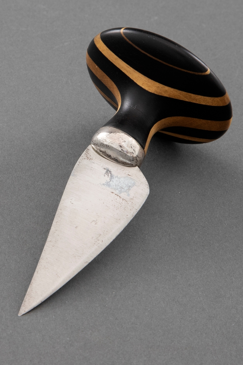 Kort blad av stål er festet til skaftet med en sølvholk. Soppformet skaft, laminert vekselsvis mørkt og lyst tre.