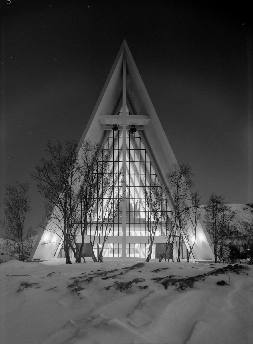 Arkitekturfoto av Tromsdalen kirke, bedre kjent som Ishavskatedralen. Med sitt avtrappede båthusformede eksteriør og sine åpne glassgavler er den blitt et landemerke i området. Kirken ble innviet 19. november 1965.