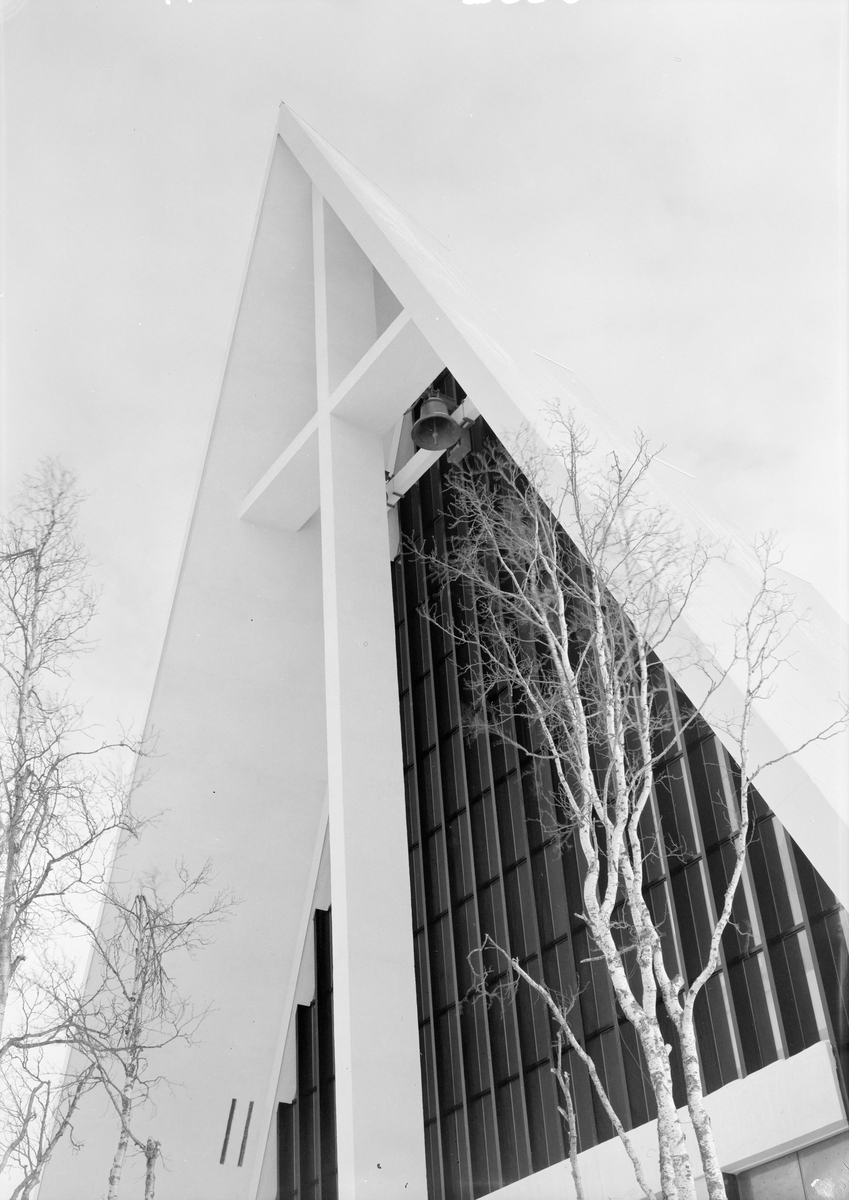 Arkitekturfoto av Tromsdalen kirke, bedre kjent som Ishavskatedralen. Med sitt avtrappede båthusformede eksteriør og sine åpne glassgavler er den blitt et landemerke i området. Kirken ble innviet 19. november 1965.