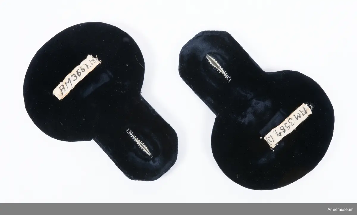 Av vitt tyg med silvergalon omkring övre delen. Runt nedre delen en förgylld plåt. Fodrade med svart sammet . Bokstäver "W.R." =Wilhelm Rex, konungens namnchiffer- med krona av guldfärgad metall.  Två guldfärgade stjärnor: gradbeteckning för ryttmästare. På högra epåletten saknas krona och en stjärna.