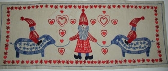 2 modeller. 1. Blått, rött, naturvitt, svart
2. Oblekt, rött, blått
2 st broderiprov finns. Mönsterritning finns i mapp BM 75104. Pris materialsats 108:-. Kalkyl finns i särskild pärm. Garnprov till två färgställningar finns. Sömnadsbeskrivning i särskild pärm.

Två broderade bonader. Motiv med tomte i mitten som håller två blå grisar i band. Tomtenissar rider på var sin gris. Konturbroderade hjärtan över mittytan. Bård med fyllda hjärtan och blommor.