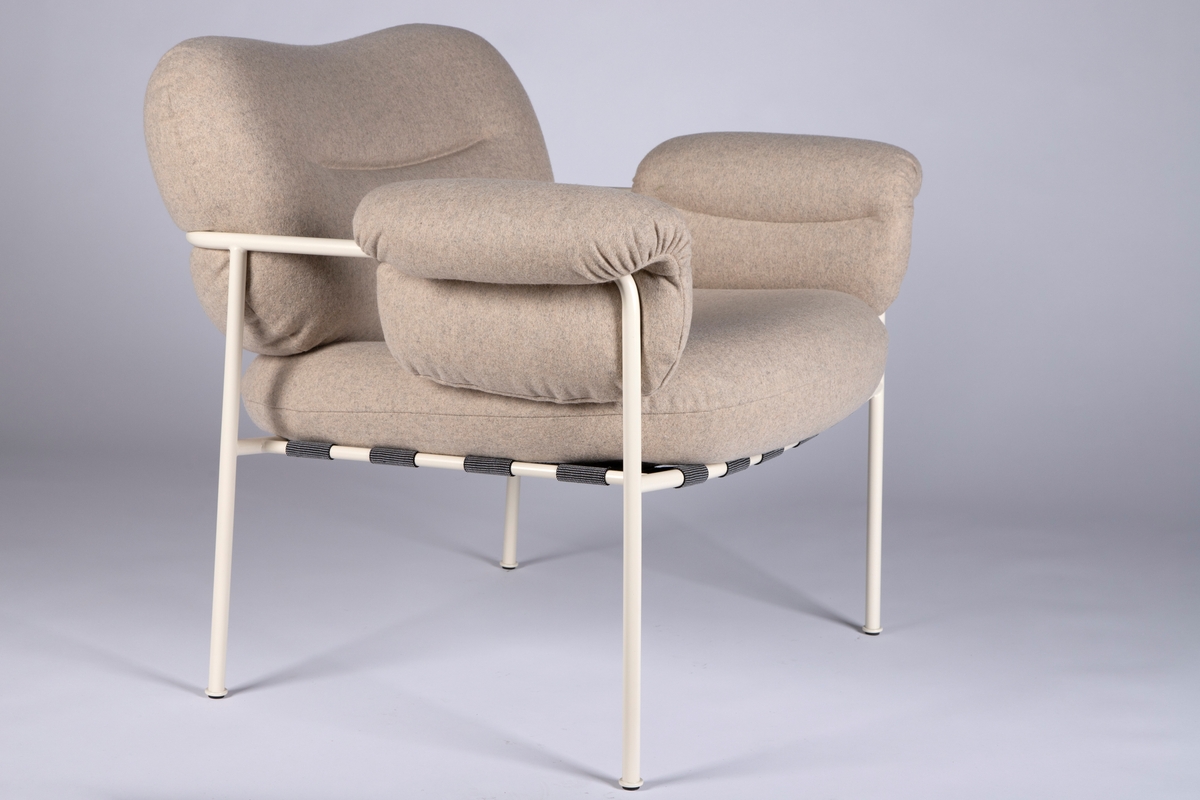 Hvitlakkert stålramme av runde, slanke rør. Runde luftige putter med hvitt ullstoff. Sete ligger i et tøynett som er festet i rammen.