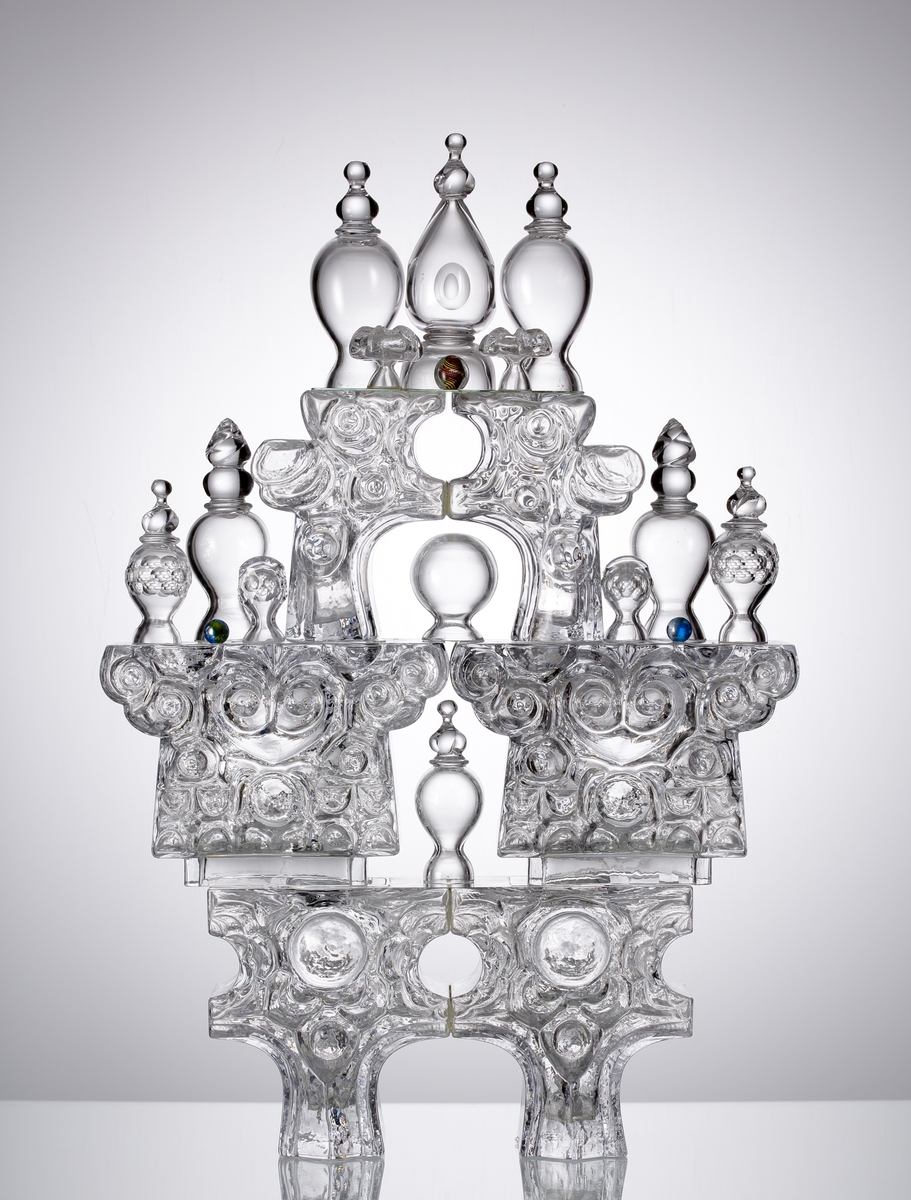 Glasskulptur. "Kristallslott".
Stiliserat slott med tinnar och torn i tre etage.
Formblåst, hyttarbetat, friblåst, slipat.
Översta plattformens spiror är monterade på en glasplatta som är spräckt. (Detta påverkar inte konstruktionen eller utseendet. 2010-01-21) .
Klarglas.

Föremålet har varit i L. Hellstens ägo i Nybro fram till 2009.

Övrigt: Kristallslottet är bland de första L.H. gjorde på Skrufs glasbruk.Han inspirerades av hyttmiljön, som han tyckte var som ett sagolandskap. Det finns tre slott, ett på Smålands Museum, ett på Nationalmuseum och ett på Röhsska Museet.
Funktion: Glasskulptur