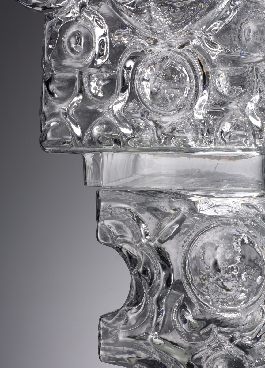 Glasskulptur. "Kristallslott".
Stiliserat slott med tinnar och torn i tre etage.
Formblåst, hyttarbetat, friblåst, slipat.
Översta plattformens spiror är monterade på en glasplatta som är spräckt. (Detta påverkar inte konstruktionen eller utseendet. 2010-01-21) .
Klarglas.

Föremålet har varit i L. Hellstens ägo i Nybro fram till 2009.

Övrigt: Kristallslottet är bland de första L.H. gjorde på Skrufs glasbruk.Han inspirerades av hyttmiljön, som han tyckte var som ett sagolandskap. Det finns tre slott, ett på Smålands Museum, ett på Nationalmuseum och ett på Röhsska Museet.
Funktion: Glasskulptur