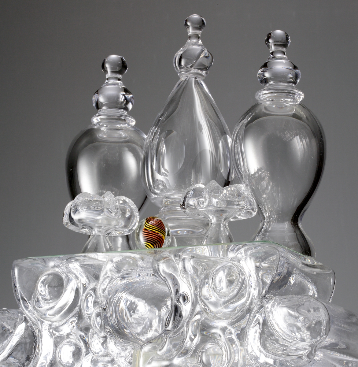Glasskulptur. "Kristallslott".
Stiliserat slott med tinnar och torn i tre etage.
Formblåst, hyttarbetat, friblåst, slipat.
Översta plattformens spiror är monterade på en glasplatta som är spräckt. (Detta påverkar inte konstruktionen eller utseendet. 2010-01-21) .
Klarglas.

Föremålet har varit i L. Hellstens ägo i Nybro fram till 2009.

Övrigt: Kristallslottet är bland de första L.H. gjorde på Skrufs glasbruk.Han inspirerades av hyttmiljön, som han tyckte var som ett sagolandskap. Det finns tre slott, ett på Smålands Museum, ett på Nationalmuseum och ett på Röhsska Museet.
Funktion: Glasskulptur
