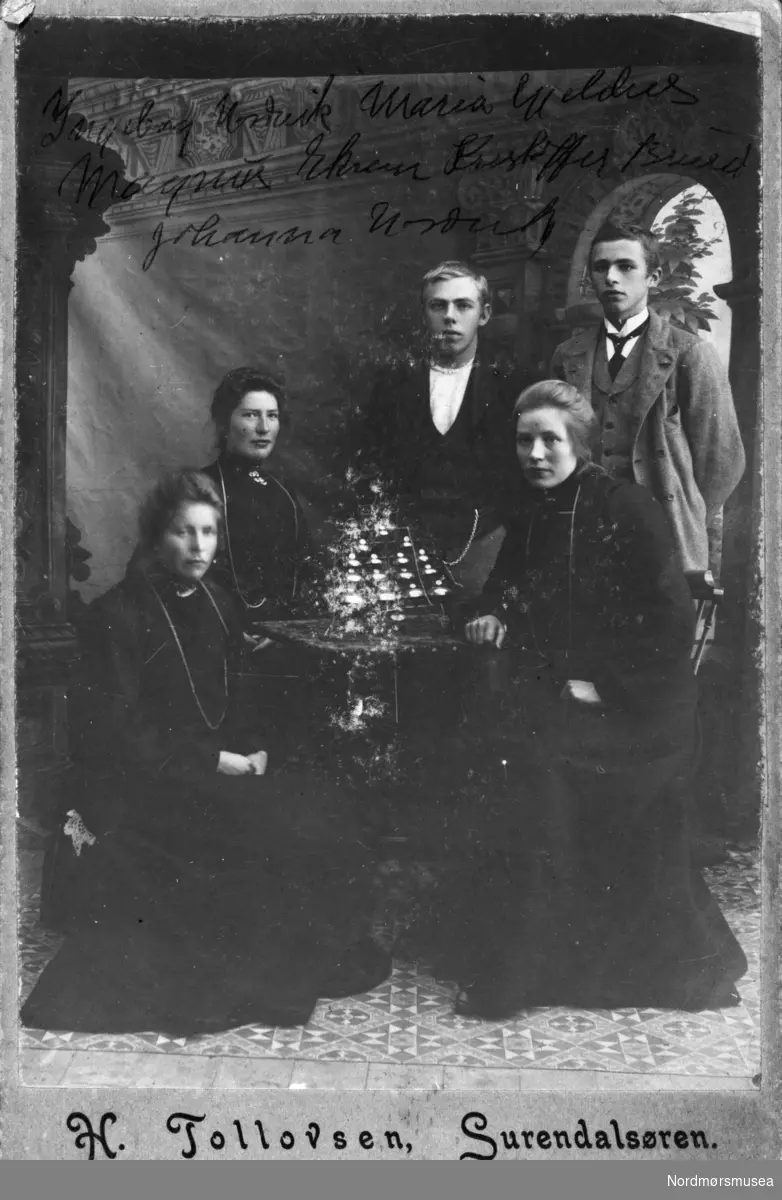 Fra venstre: Ingeborg Nordvik, Maria Gjeldnes, Johanna Nordvik. Bak: Magnus Ekrem, Kristoffer Bruset. Fotograf er H. Tollovsen i Surnadal. Datering er ca. 1905. Fotografiet er fra en fotosamling bestående av fire album gitt (digitalt) i gave til Nordmøre museum av Astrid Kvendbø. Originalmaterialet er returnert eier. Fra Nordmøre museums fotosamlinger.