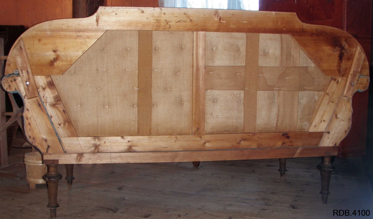 En 3-seters sofa. Rygg og sete av stoff, føtter og kanter av tre. Fire, runde føtter. Stoffet er i et grønt blomstermønster. Et armlene på hver side, som skrår utover. To runde detaljer på hver av armlenene. 