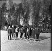 Realskolan vinterlov januari 1961. Några unga männsikor står uppställda framför kameran för fotografering. De har skridskor på fötterna och de står på en snöklädd isbana. Alla bär pälsmössa eller sjalett på huvudet.