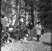 Realskolans vinterlov januari 1961. En klunga unga personer fikar vid en strandkant. Det är vinter och stranden är istäckt. 

Negativet är skadat och en stor reva syns tvärs över bilden.