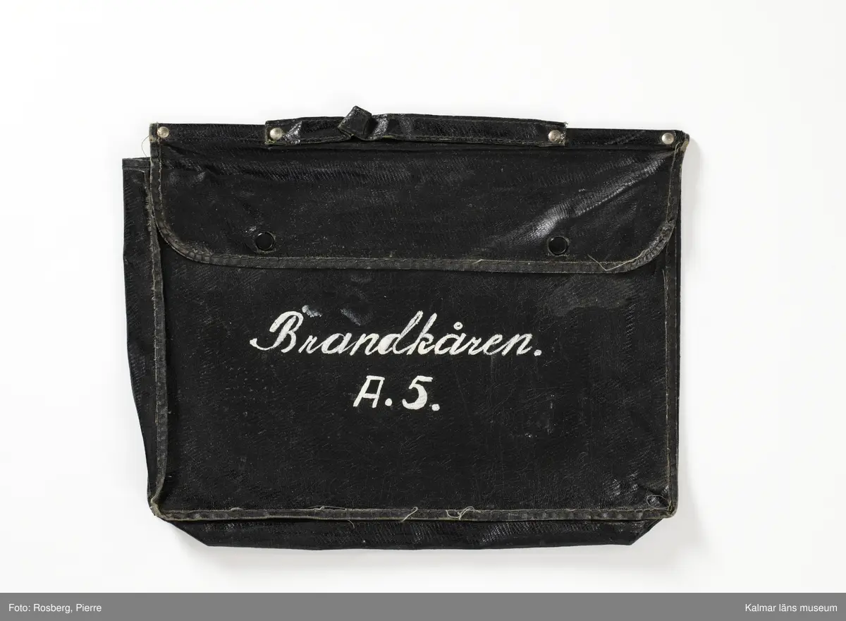 KLM 46618:1:1-16. Väska. :1: Svart väska av plastmaterial, på utsidan svart och insidan grön. Lock som stängs med tryckknappar. Handtag. Påmålad text i vitt framsida: Brandkåren A.5. Väskan innehåller pappersdokument :1:1-16.

:1:1. Allmän kungörelse. Nr 69. Luftskyddsövningar i luftskyddsorterna Kalmar, Nybro och Västervik. Länsstyrelsen Kalmar 1944. Kalmar Tryckeri Aktiebolag. 
:1:2. Övningstekniska anvisningar för luftskyddsövningar, Länsstyrelsen.
:1:3. Rapportblock. Sven Lindegrens tryckeri, Kalmar.
:1:4. Rapportblock. Sven Lindegrens tryckeri, Kalmar.
:1:5. Rapportblad, häftat på masonitskiva.
:1:6. Meddelandeblock. Sven Lindegrens tryckeri, Kalmar.
:1:7. Meddelandeblock. Sven Lindegrens tryckeri, Kalmar.
:1:8. Telefonförteckning för luftskyddet i Kalmar 1 sko. Sju sidor, häftad. Upprättad den 27/1 1944.
:1:9. Utrustningslista. Brandkårsavdelning A5.
:1:10. P.M. Till tjänstecheferna.
:1:11. Föreskrifter vid ockupation och vid hot om ockupation, två sidor. Upprättat för Luftskyddsinspektionen och inkom den 10/9 1943. Sida två upprättat den 7/10 1943.
:1:12. Dokument rörande uppställningsplatsen och förläggningsstället Funkaboskolan för Brandkårsavdelning A.5.
:1:13. Förutsättning och program för luftskyddsövning i Kalmar den 20-21 mars 1944.
:1:14. P.M. för tjänstegrenschefer och avdelningschefer m.fl. vid brandtjänsten, fram och baksida.
:1:15. Förteckning över rapportställe, förteckning över brandtjänsten.
:1:16. Exempel på förfarande vid skadeplats.