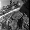 rasberget vid länsgränsen 1961. Närbild på en bergvägg och strålen från en vattenkanon som riktas mot toppen av bergväggen.