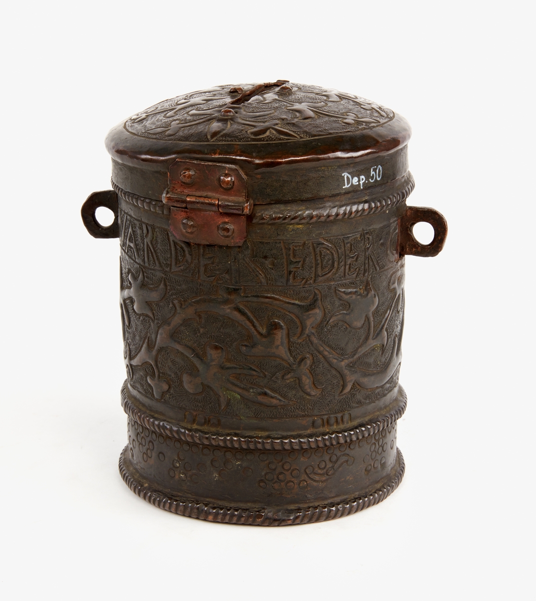 Sparbössa av koppar. Cylindrisk, med lock. Rikt dekorerad med ornament samt text: "Gifwer så varder eder givit 1666". På locket en skåra för myntinkast, på undersidan är sämskskinn fäst i en fastnitad kopparinsats. En ögla på var sida. Låsbygel mitt fram.