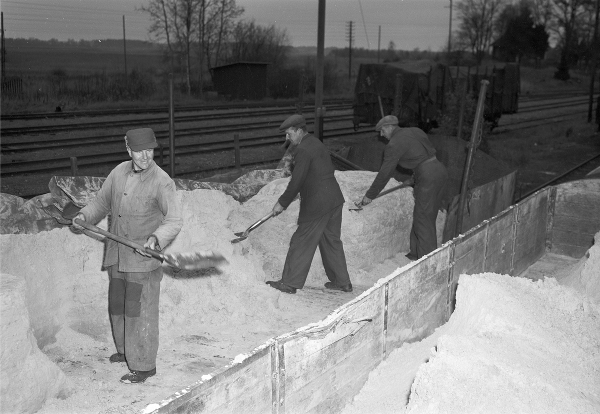 Tre män skottar snö vid banvall, Uppland