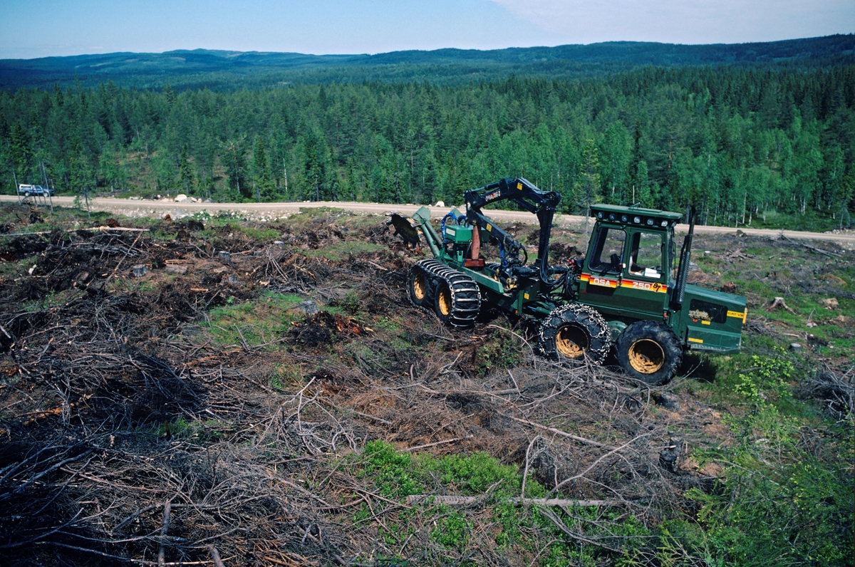 Rammestyrt traktor med markbredningsaggregat, fotografiert på ei snauflate ved Holmsetra i Hedmark. Maskinen er fra den svenske produsenten Östbergs Fabriks AB - vanligvis forkortet ÖSA - i Ovanåker kommine i Gävleborgs len i Sverige. I nordisk sammenheng var dette en pionerbedrift i markedet for motoriserte skogsmaskiner. I 1993 ble ÖSA kjøpt av den amerikanske konkurrenten Timberjack (John Deere)ksjonen ble flyttet til Finland. Marberedninga ble utført ved hjelp av et eget aggregat, en hydraulisk arm med et roterende element - en slags stor opp-ned-vendt tallerken med ståltenner i ytterkanten - som ble bak den rammestyrte maskinen mens den ble kjørt fram og tilbake over hogstflata. Poenget var å flå av markvegetasjonen og humuslaget slik at man blottla mineraljorda. Dette skapte bedre spirevilkår for frø fram omkringstående skog. De spirende frøene slapp, i hvert fall i denne tidlige fasen, konkurranse om lys og fuktighet fra annen markvegetasjon.