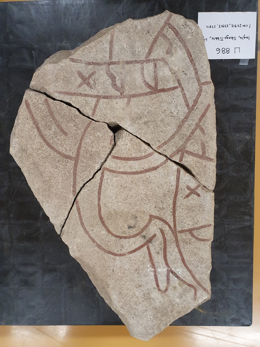 Runstensfragment med runslinga på två sidor, röd- och svartmålade. Inskrift  A: "...ina  x  fitiR...", "  B: "...ur  x  ...a x k...", (= ... denna (sten) efter...).