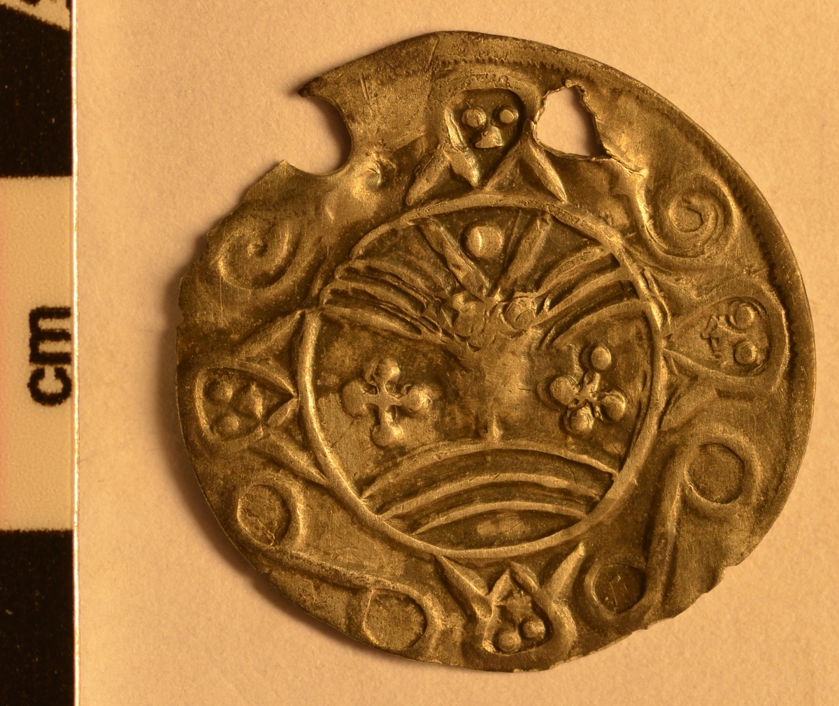 Motiv advers: Ansikt med stråler og bart. Fire mindre masker, to 8-tallsymbol og to slanger i ring rundt. 

Motiv revers: Hjort som vender framover, slange foran mulen, solsymbol bak og trikvetra symbol under. 