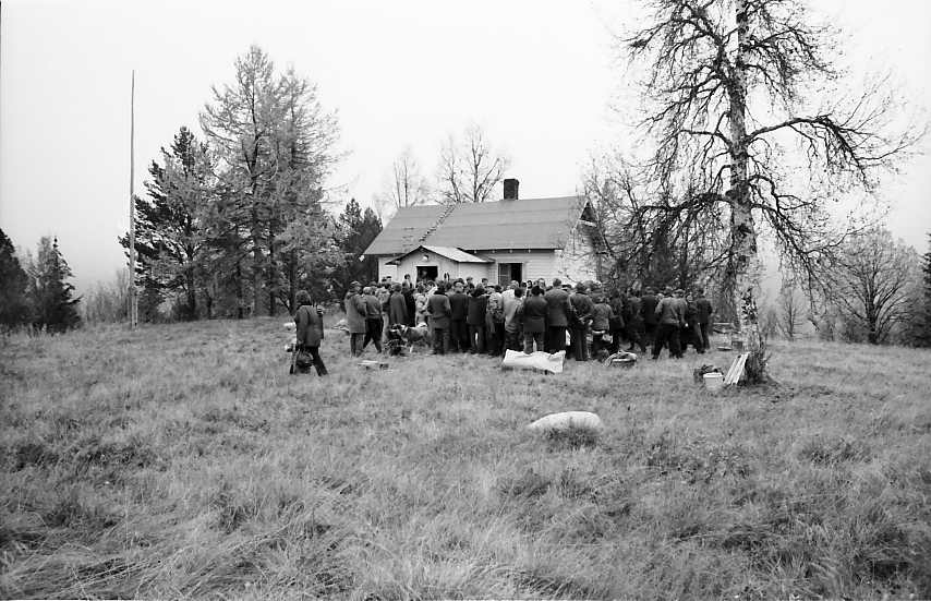 Auksjon, utendørs ansamling m. ryggen til. 