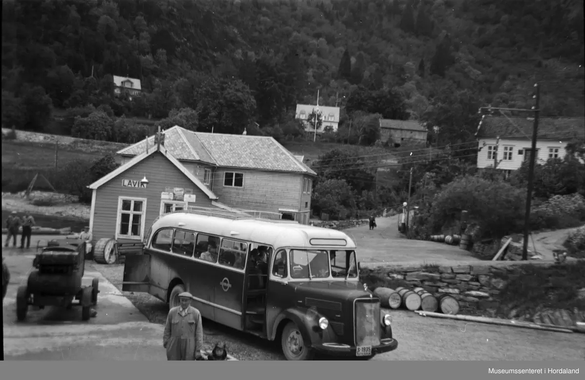Motiv frå Lavik med menneske ved buss frå Firda Billag.