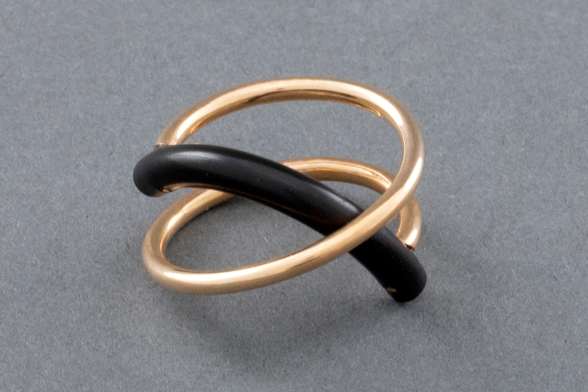Ring laget av gulltråd med form som en åpen spiral tvunnet 1 1/2 gang. Et halvsirkelformet gummistykke, litt tykkere enn gulltråden er festet til hver ende av gullspiralen. Gummistykket blir slik stående på tvers av denne.