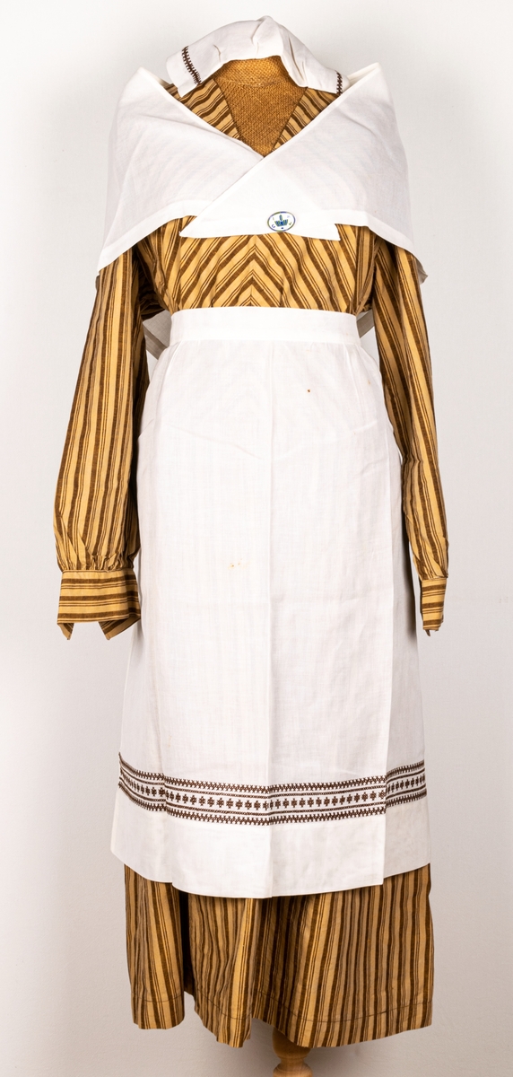 Bomhus Kooperativa kvinnogillesdräkt. Brunrandig klänning med förkläde.