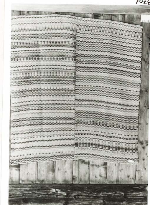 Teppe i krokbragd i mange fargar. Renning: 26/10 cm. tvunnet lintråd. Innslag: 2trds ullgarn. Teppet er skjøtt på midten, og bordane møtes tilfeldig i skøyten.