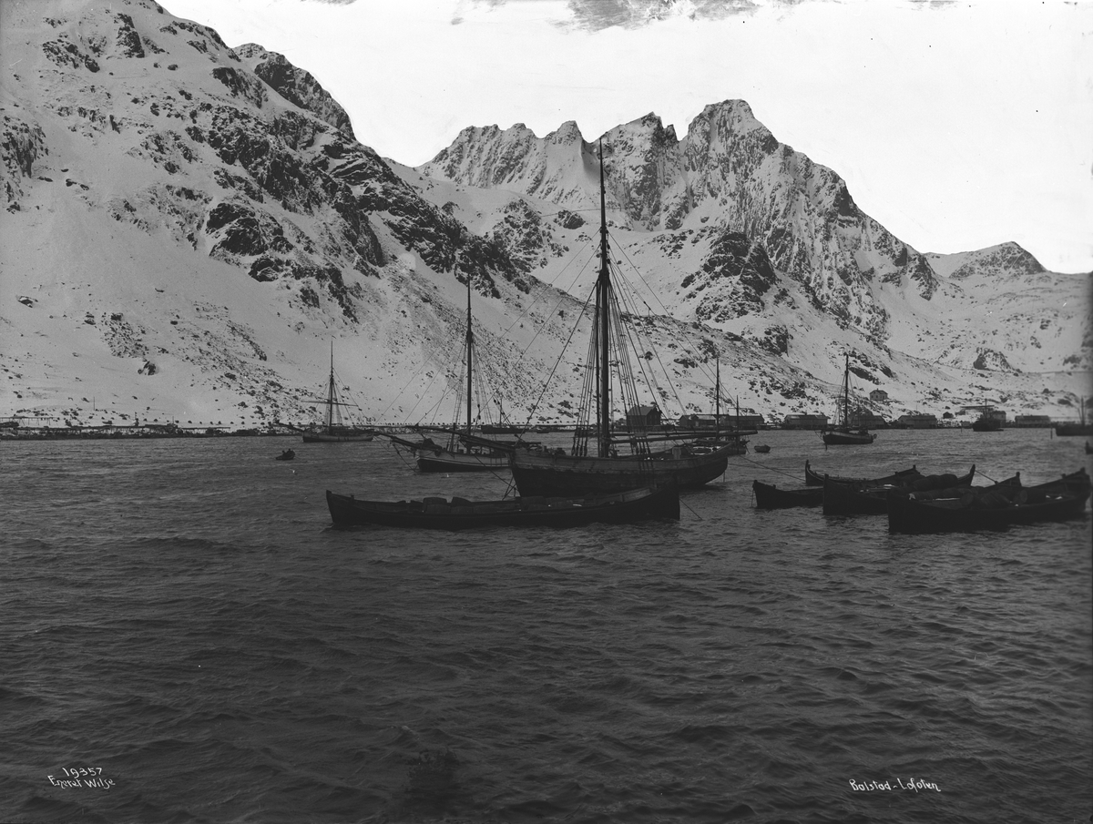 Fortøyde fiskebåter og fjell dekket av snø i bakgrunnen i Ballstad på Vestvågøy, april 1917.